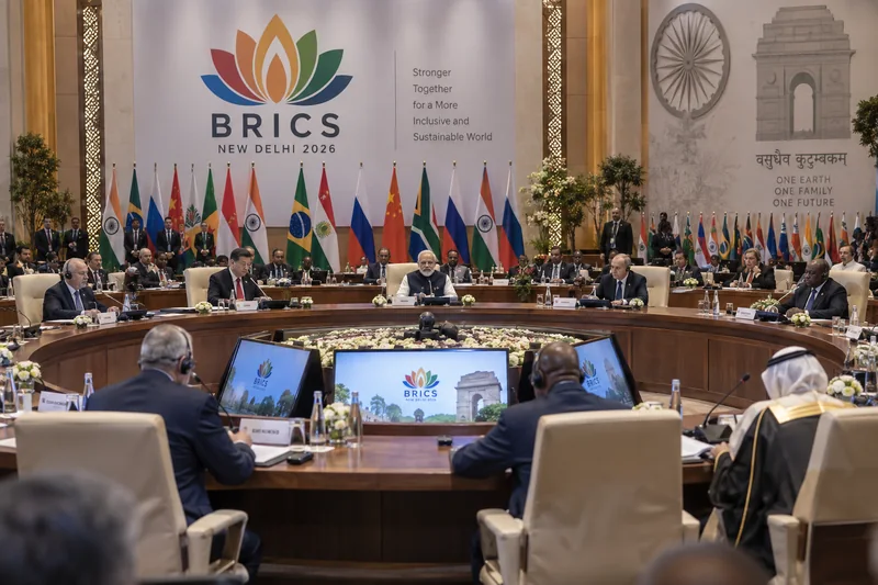 Scena editoriale contestuale ordinaria generata con IA di una sala del vertice BRICS a New Delhi con delegazioni e bandiere, senza incontri specifici ricostruiti