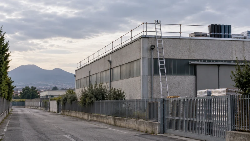 Illustrazione editoriale IA di un capannone e di una strada isolata nell'area napoletana, senza persone; nessuna ricostruzione dell'incidente.
