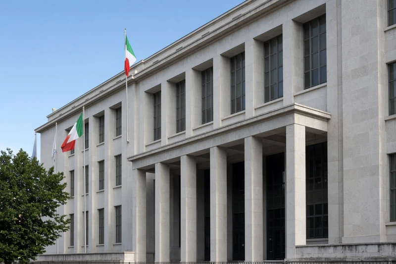 Facciata sobria di un edificio giudiziario italiano con bandiere; illustrazione editoriale IA non documentaria.