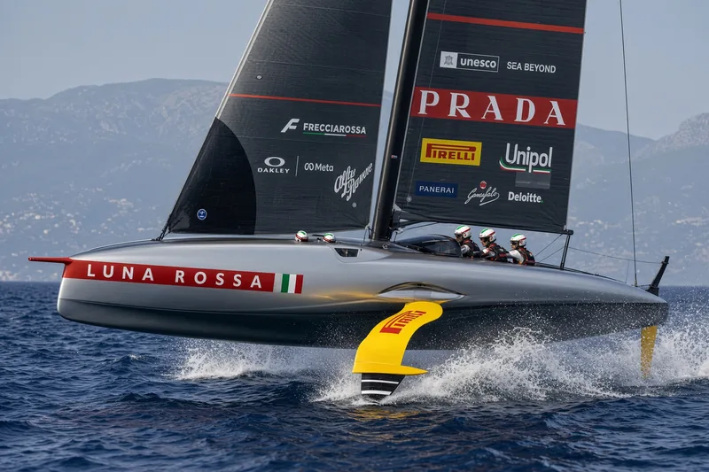 Barca AC75 Luna Rossa Prada in volo su foil nel Mediterraneo; illustrazione editoriale IA non documentaria.
