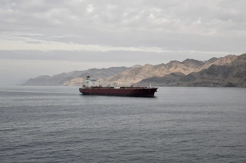 Scena editoriale del luogo generata con IA: petroliera intatta a distanza nello Stretto di Hormuz, senza incendio né persone; non è una fotografia documentaria dell’attacco.