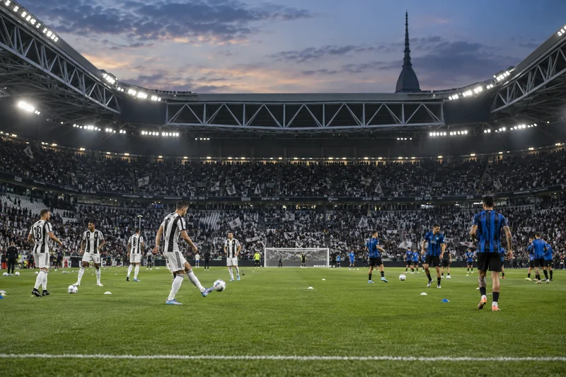 Scena editoriale contestuale generata con IA: calciatori in bianconero e nerazzurro si preparano a Juventus-Atalanta; non è una fotografia documentaria.