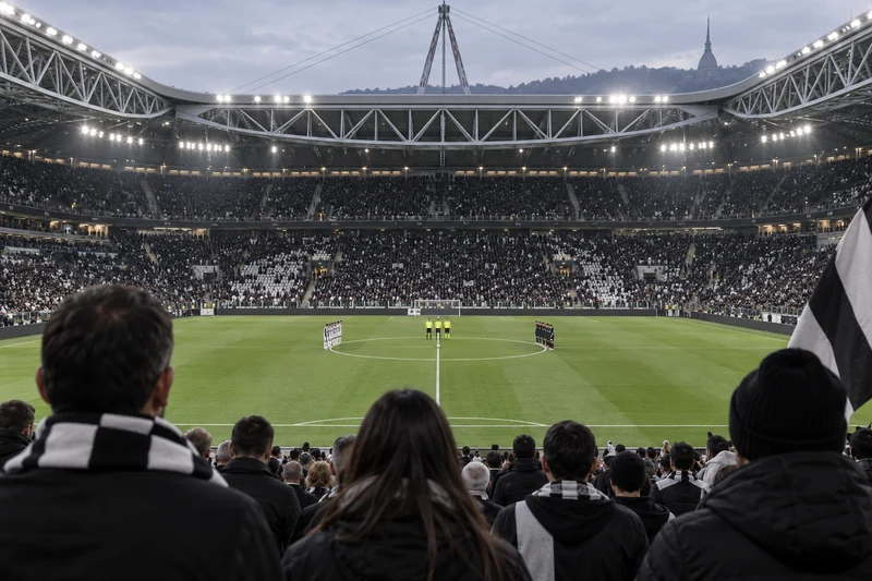 Stadio editoriale IA di Torino durante un minuto di silenzio prima di una partita di calcio; scena non documentaria.