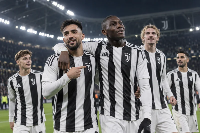 Scena editoriale contestuale generata con IA con Nico González e Randal Kolo Muani insieme ad altri giocatori della Juventus in uno stadio di Torino dopo una partita europea; non documentaria.