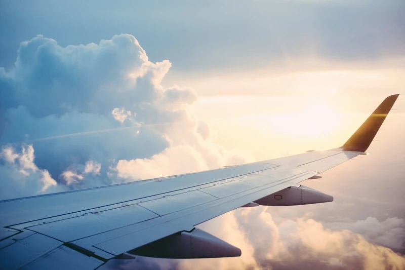 Interno di aereo di linea con corridoio e sedili visti da dietro; illustrazione editoriale IA non documentaria.