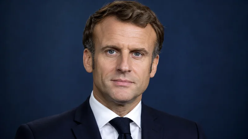 Ritratto editoriale neutrale di Emmanuel Macron generato con IA, su sfondo blu; immagine non documentaria.