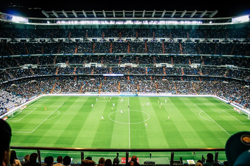 Stadio Etihad e stemma Manchester City sul prato; illustrazione editoriale IA non documentaria.