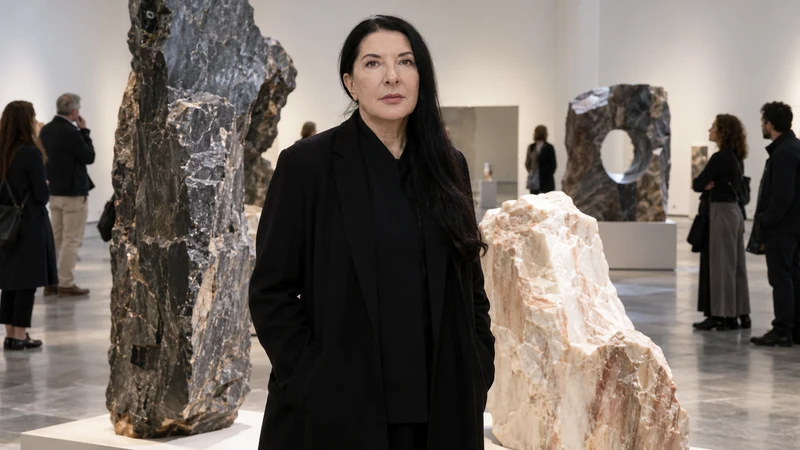 Illustrazione editoriale IA di Marina Abramović in una galleria accanto a opere minerali; non documenta l’allestimento reale.