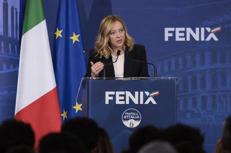 Illustrazione editoriale generata con IA: Giorgia Meloni parla a un podio con le scritte FENIX e Fratelli d’Italia, davanti alle bandiere italiana ed europea; non è una fotografia documentaria.