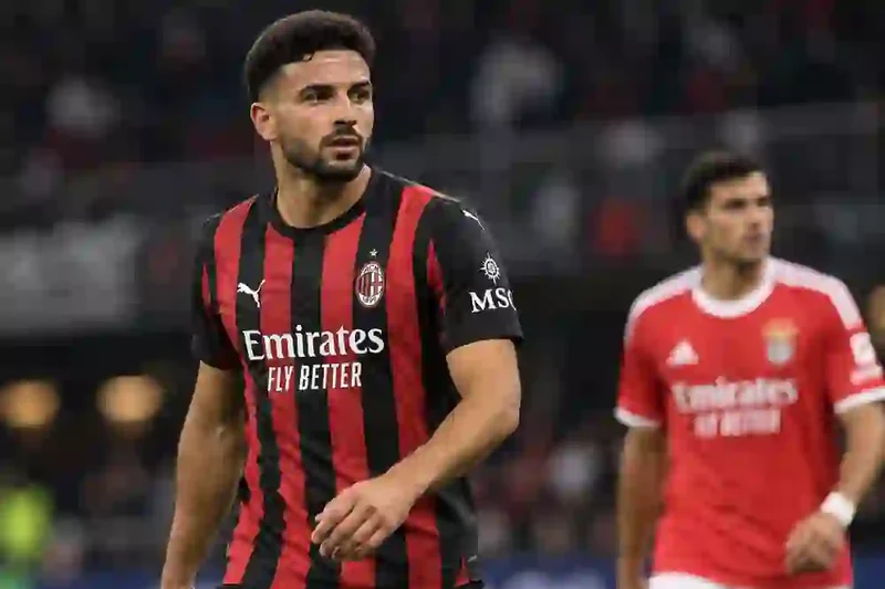 Scena editoriale contestuale generata con IA: un calciatore del Milan in maglia rossonera, con un avversario del Benfica sullo sfondo in uno stadio serale, per rappresentare Milan-Benfica.