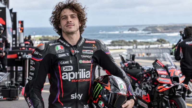 Somiglianza sintetica editoriale di Marco Bezzecchi nel paddock Aprilia a Phillip Island; immagine non documentaria.