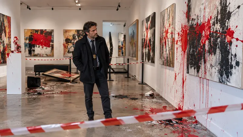Interno di una galleria romana con opere imbrattate e un investigatore che osserva i danni