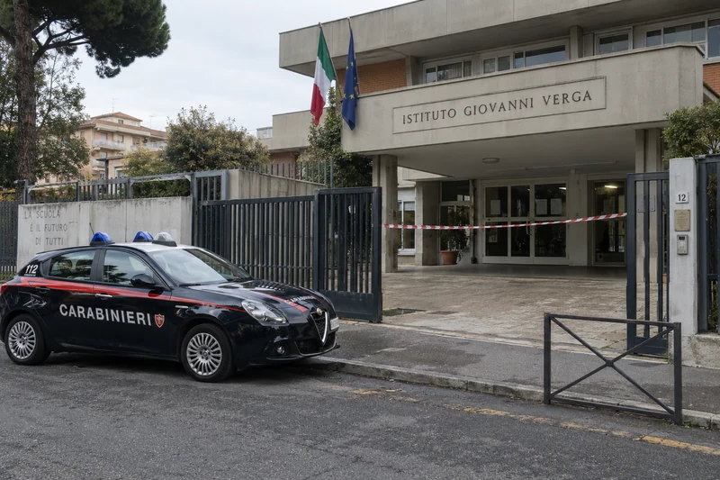 Illustrazione editoriale generata con IA: ingresso dell’Istituto Giovanni Verga di Roma con auto dei Carabinieri, scritte CARABINIERI e 112 visibili, senza persone o scene di violenza; non è una fotografia documentaria.