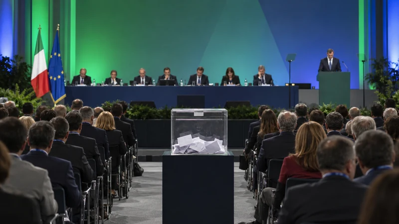 Illustrazione editoriale IA di un congresso politico italiano con urna per il voto e delegati in sala; scena simbolica non documentaria.