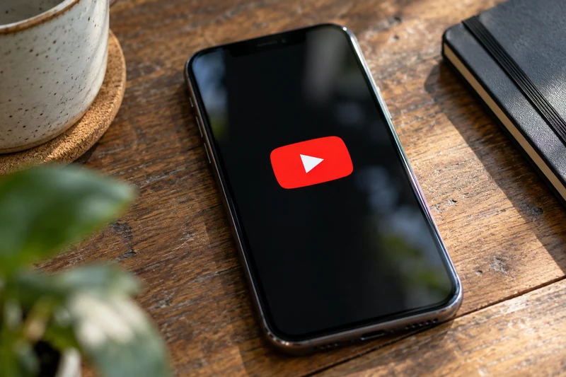 Uno smartphone con il simbolo YouTube, illustrazione IA senza persone o riferimenti identificativi ai minori.