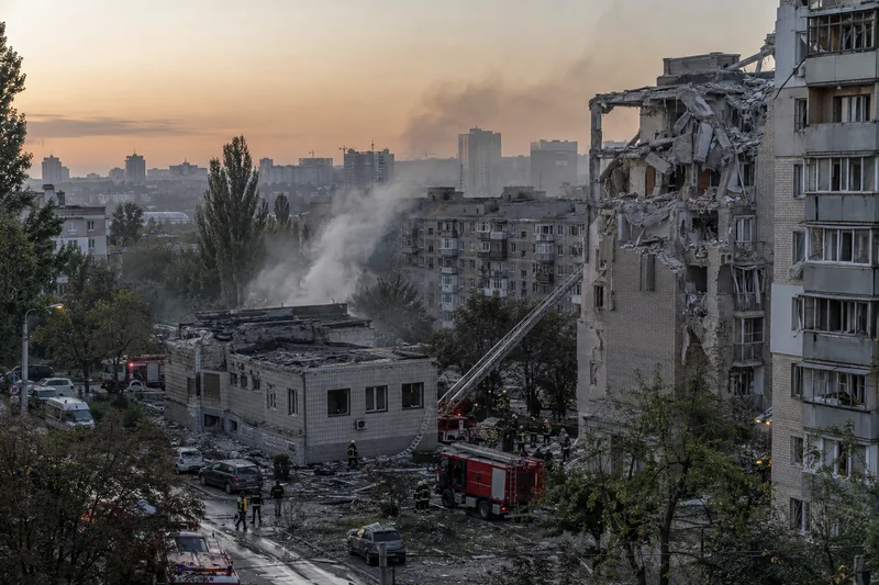 Scena editoriale sensibile generata con IA di edifici danneggiati in una città ucraina con soccorritori al lavoro, senza vittime visibili