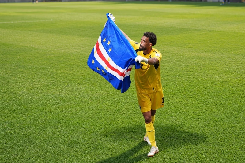 Vozinha portiere di Capo Verde in maglia gialla con bandiera nazionale in campo; illustrazione editoriale IA non documentaria.