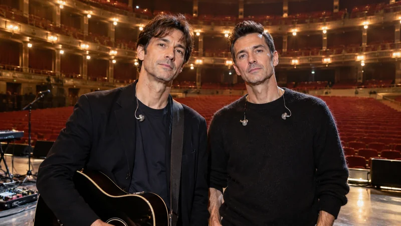 Illustrazione editoriale IA con somiglianza sintetica di Matteo Maffucci e Thomas De Gasperi, gli Zero Assoluto, sul palco di un teatro vuoto; non documenta un concerto reale.